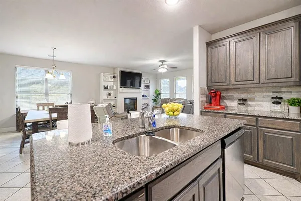 a kitchen with granite countertop a sink a counter top space cabinets and stainless steel appliances