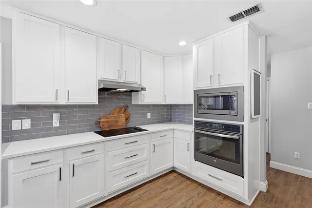 a large white kitchen with a sink and dishwasher with wooden floor