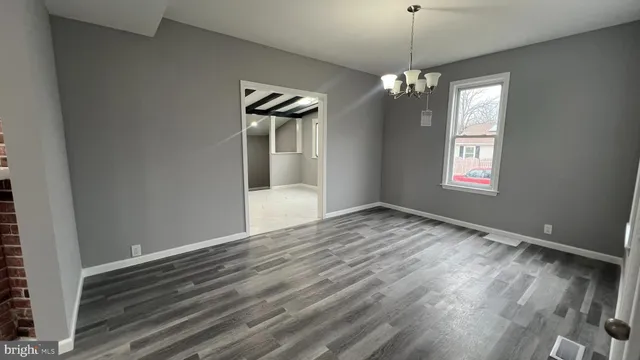 a view of an empty room with window and wooden floor