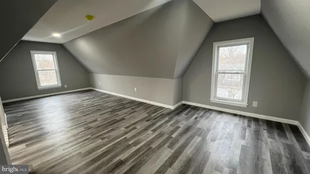 a view of an empty room with wooden floor and window