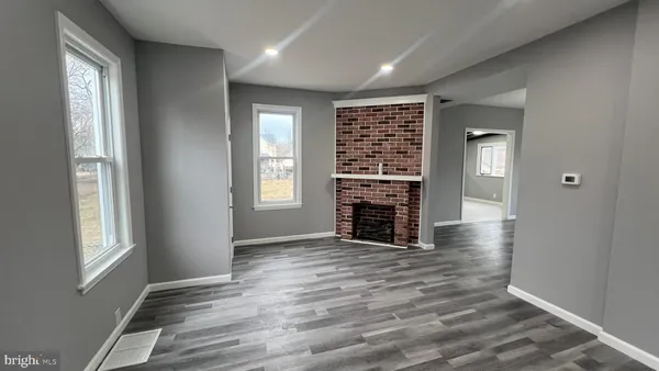 an empty room with wooden floor cabinet and windows