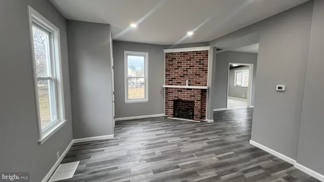 an empty room with wooden floor cabinet and windows