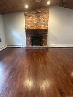 an empty room with wooden floor fireplace and windows