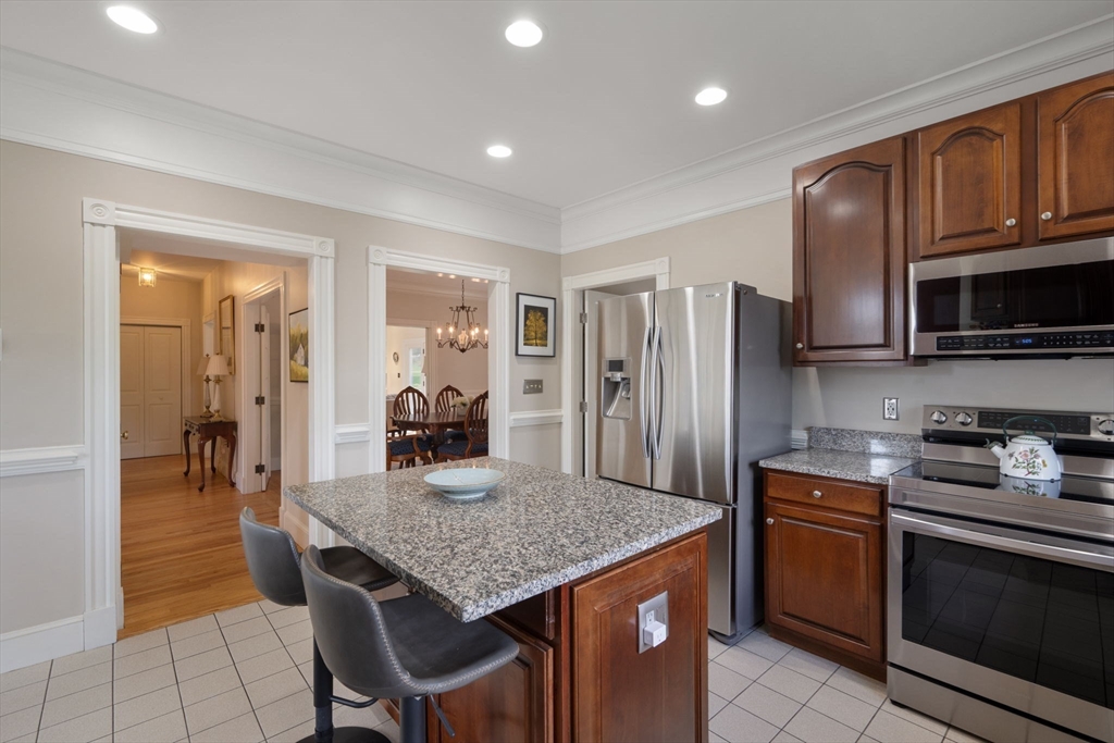 4 Harborview Road Hull, MA 02045 - Photo 7 of 38 a kitchen with granite countertop kitchen island stainless steel appliances a stove refrigerator a microwave oven with a dining table and chairs