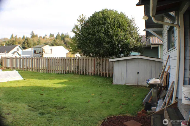 a view of a backyard with wooden fence and trees