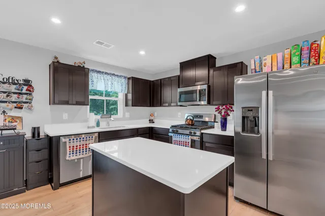 a kitchen with stainless steel appliances kitchen island granite countertop a sink stove and refrigerator
