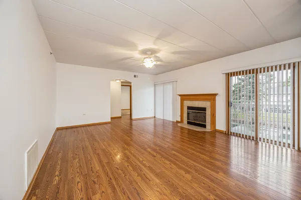 a view of empty room with wooden floor and fireplace