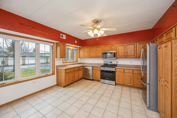 a kitchen with stainless steel appliances granite countertop a stove top oven a sink dishwasher and a refrigerator with wooden floor