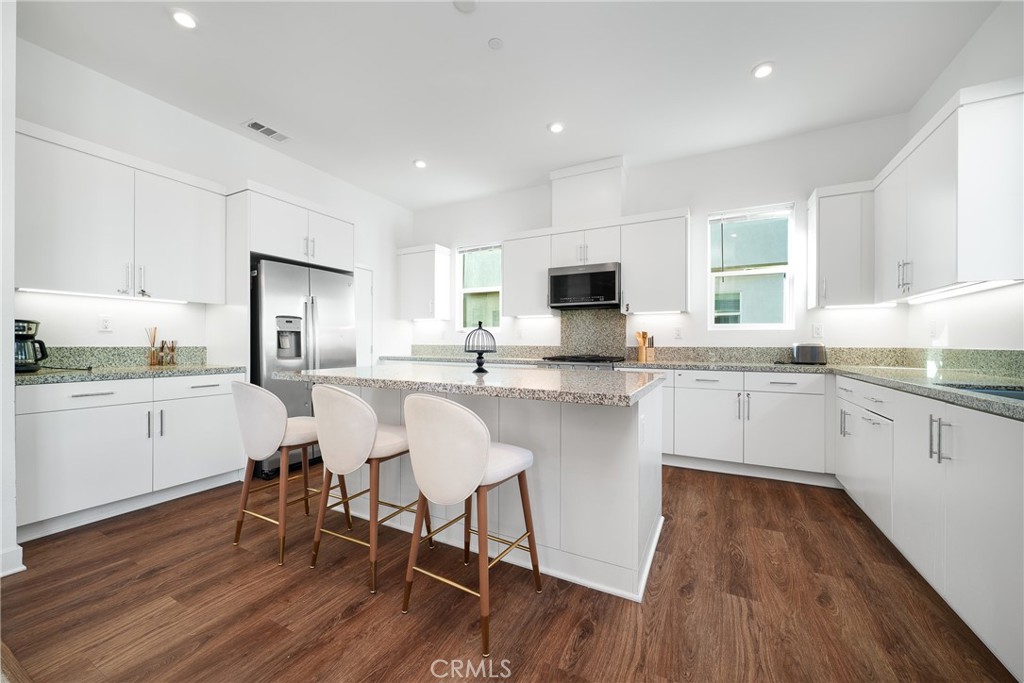 1602 West Bushell Street Anaheim, CA 92805 - Photo 15 of 31 a kitchen with a sink a stove a refrigerator and white cabinets with wooden floor