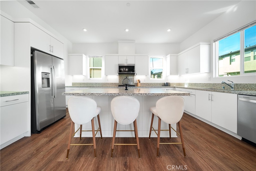 1602 West Bushell Street Anaheim, CA 92805 - Photo 16 of 31 a kitchen with stainless steel appliances granite countertop a dining table chairs refrigerator sink and cabinets