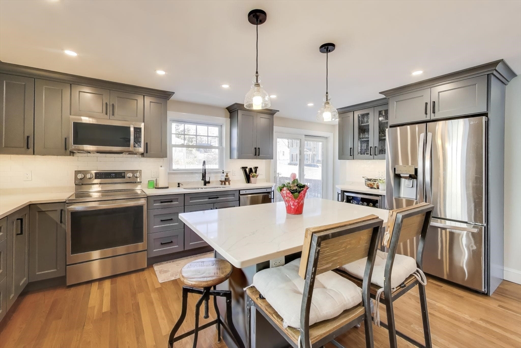 76 Dale Street Boston, MA 02131 - Photo 12 of 29 a kitchen with stainless steel appliances granite countertop a refrigerator a stove a sink dishwasher a dining table and chairs with wooden floor