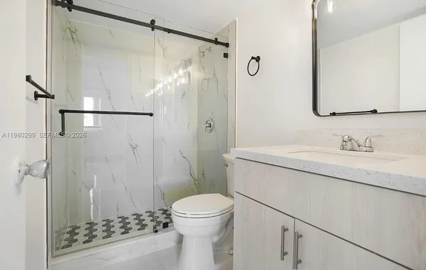 a bathroom with a sink vanity granite toilet and shower