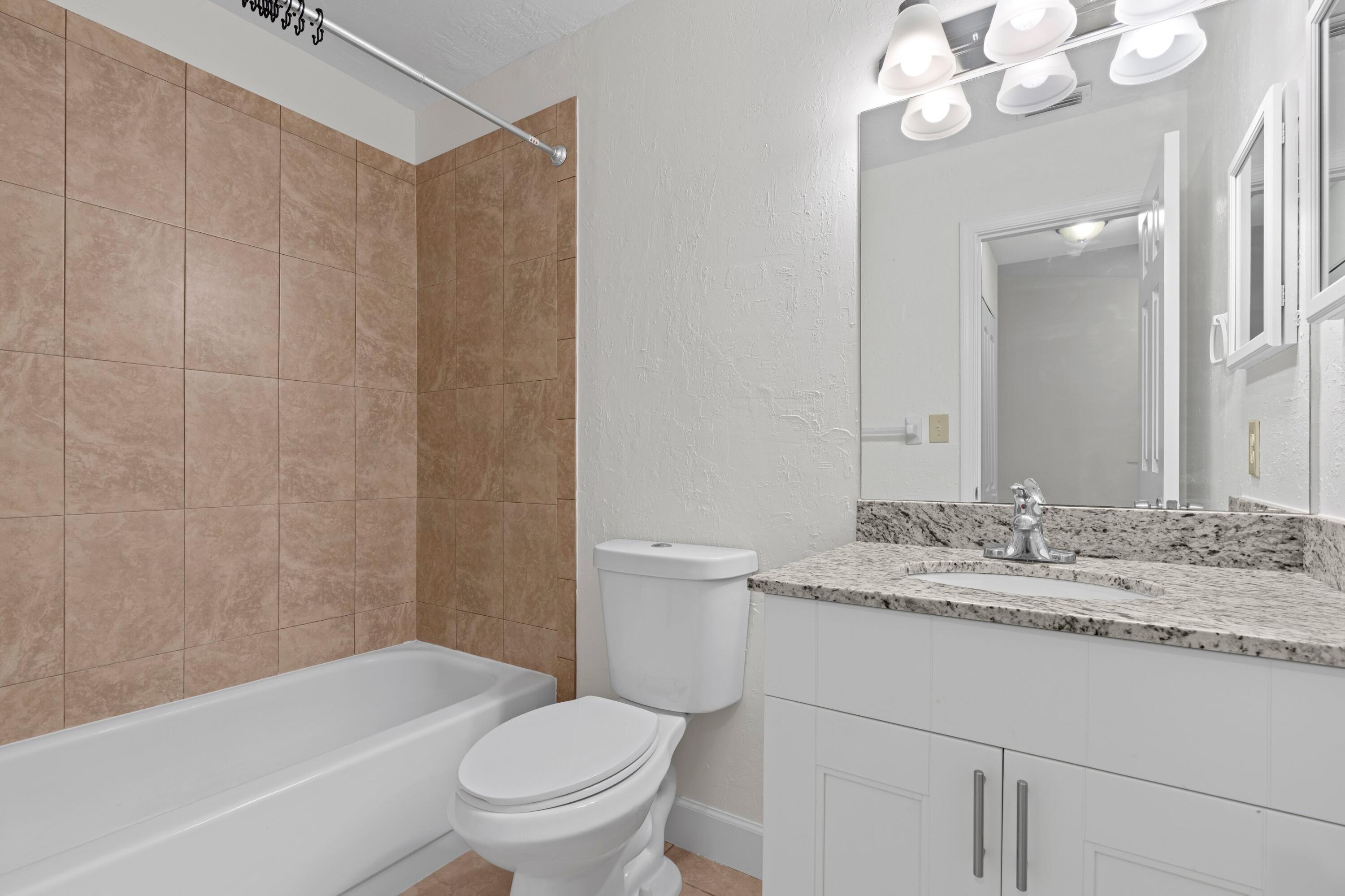 3139 Millwood Terrace, Unit M225 Boca Raton, FL 33431 - Photo 12 of 25 a bathroom with a granite countertop sink toilet and shower