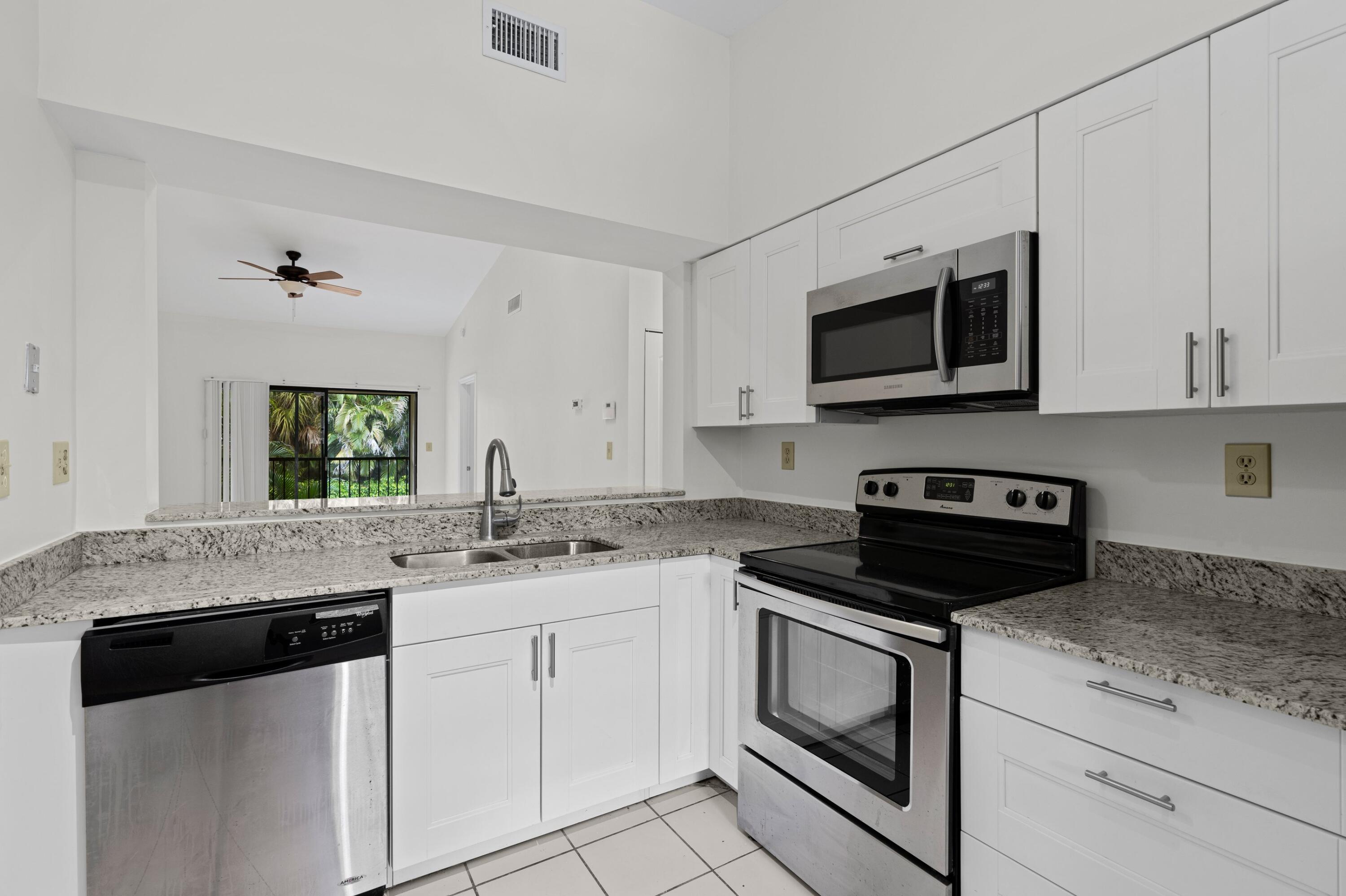 3139 Millwood Terrace, Unit M225 Boca Raton, FL 33431 - Photo 4 of 25 a kitchen with granite countertop white cabinets appliances and a sink