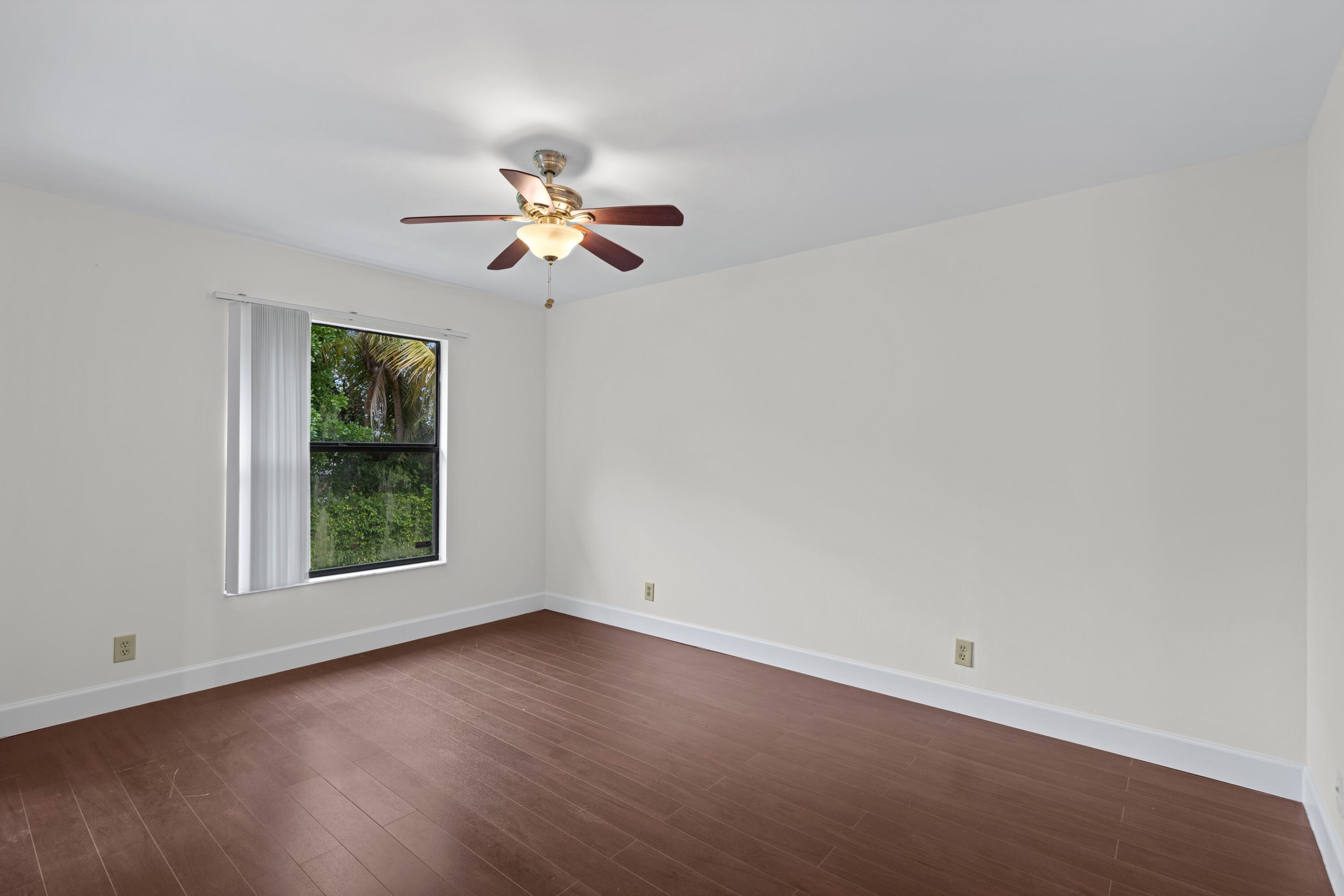 3139 Millwood Terrace, Unit M225 Boca Raton, FL 33431 - Photo 8 of 25 an empty room with wooden floor ceiling fan with window