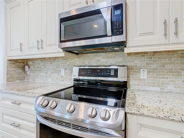 a kitchen with granite countertop cabinets stove top oven and microwave