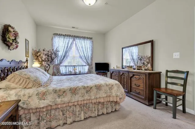a bedroom with a bed a table and large windows