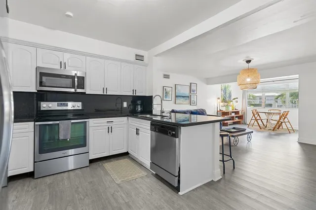 a kitchen with stainless steel appliances kitchen island granite countertop a stove top oven a sink a counter space and cabinets