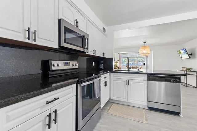 a kitchen with granite countertop white cabinets and stainless steel appliances