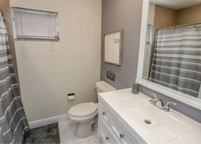 a living room with stainless steel appliances furniture a flat screen tv and kitchen view