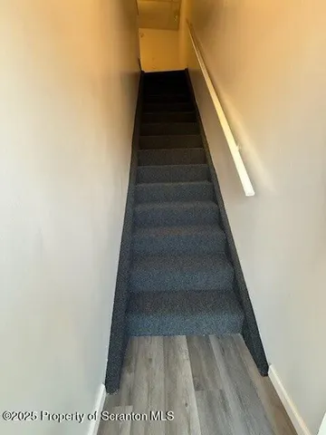 an empty room with wooden floor chandelier fan and windows