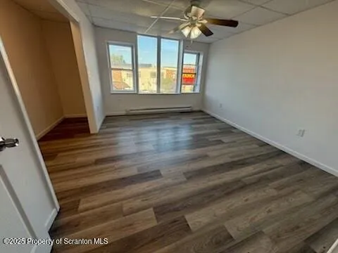 an empty room with wooden floor fan and windows