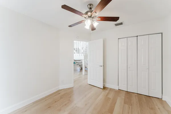 an empty room with wooden floor fan and windows