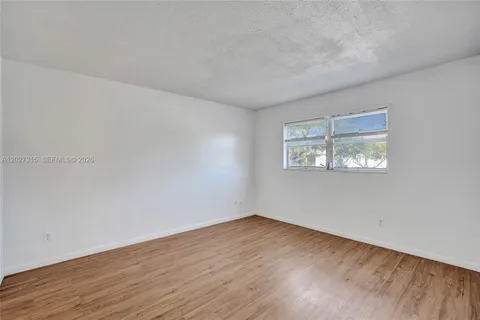a view of an empty room with wooden floor and closet