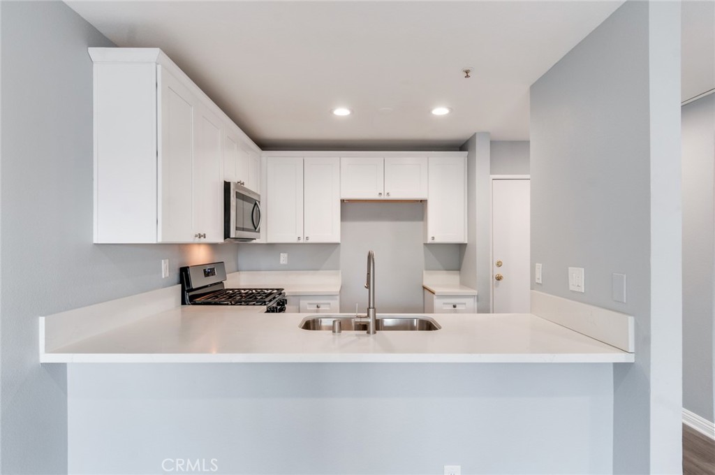 450 East 4th Street, Unit 221 Santa Ana, CA 92701 - Photo 14 of 43 a kitchen with kitchen island granite countertop a sink white cabinets and a stove