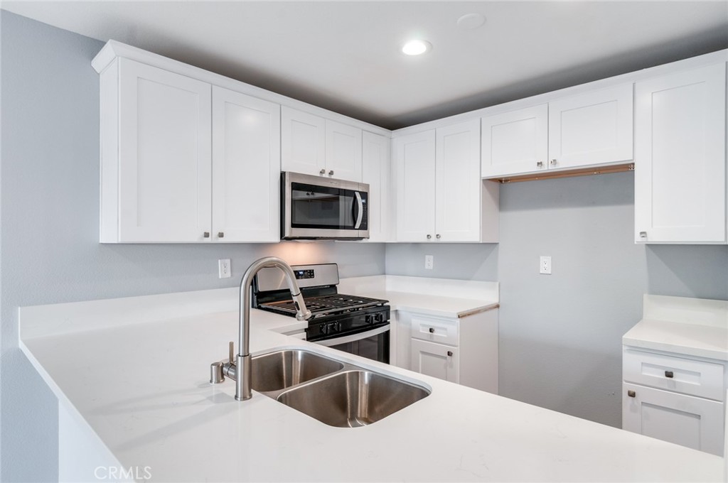 450 East 4th Street, Unit 221 Santa Ana, CA 92701 - Photo 15 of 43 a kitchen with white cabinets a sink and stainless steel appliances