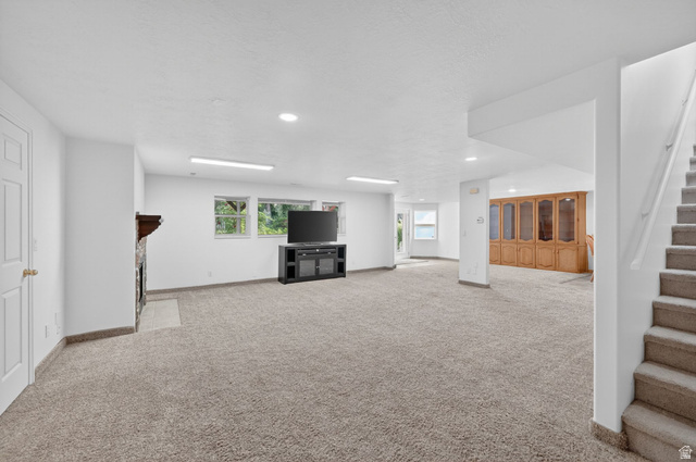 883 East 700 South Springville, UT 84663 - Photo 33 of 59 Spacious carpeted room featuring a stone fireplace with a wood mantle, recessed lighting, and multiple windows