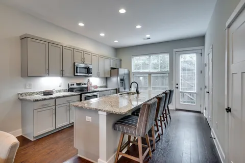 a kitchen with stainless steel appliances granite countertop a sink a stove and a wooden floors
