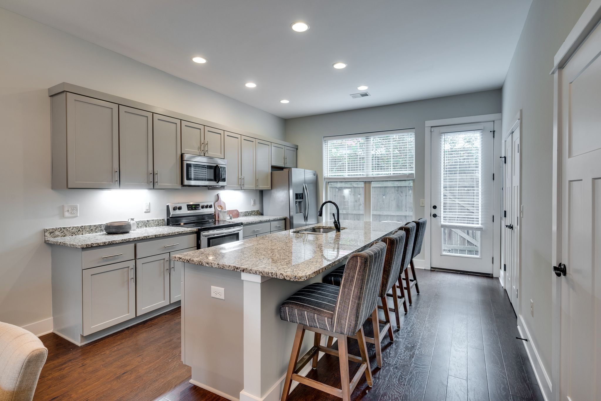 1106 Stratford Avenue, Unit 3 Nashville, TN 37216 - Photo 7 of 23 a kitchen with stainless steel appliances granite countertop a stove a sink dishwasher a microwave oven and a dining table with wooden floor
