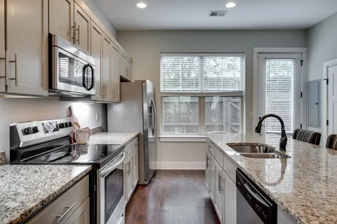 a kitchen with granite countertop kitchen island sink stove and white cabinets
