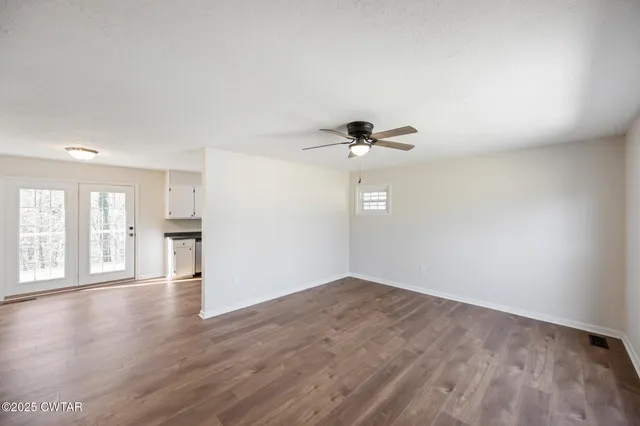 a view of an empty room with wooden floor and a window