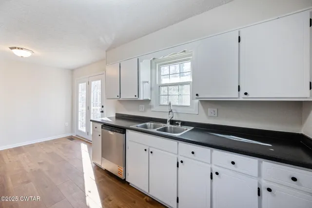 a kitchen with granite countertop white cabinets and a sink