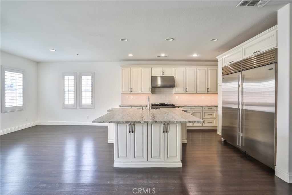 2795 Devonshire Lane Ontario, CA 91762 - Photo 14 of 50 a kitchen with stainless steel appliances granite countertop a refrigerator a sink a stove and white cabinets with wooden floor