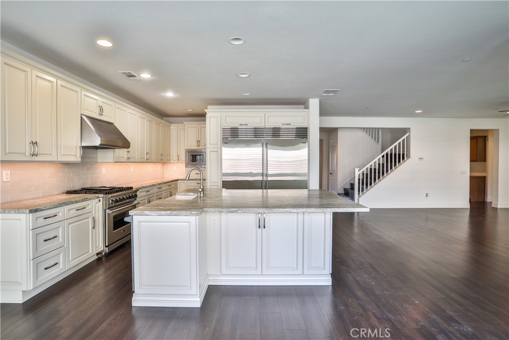 2795 Devonshire Lane Ontario, CA 91762 - Photo 15 of 50 a kitchen with granite countertop a stove a sink and white cabinets with wooden floor