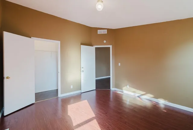 a view of an empty room with a window and wooden floor
