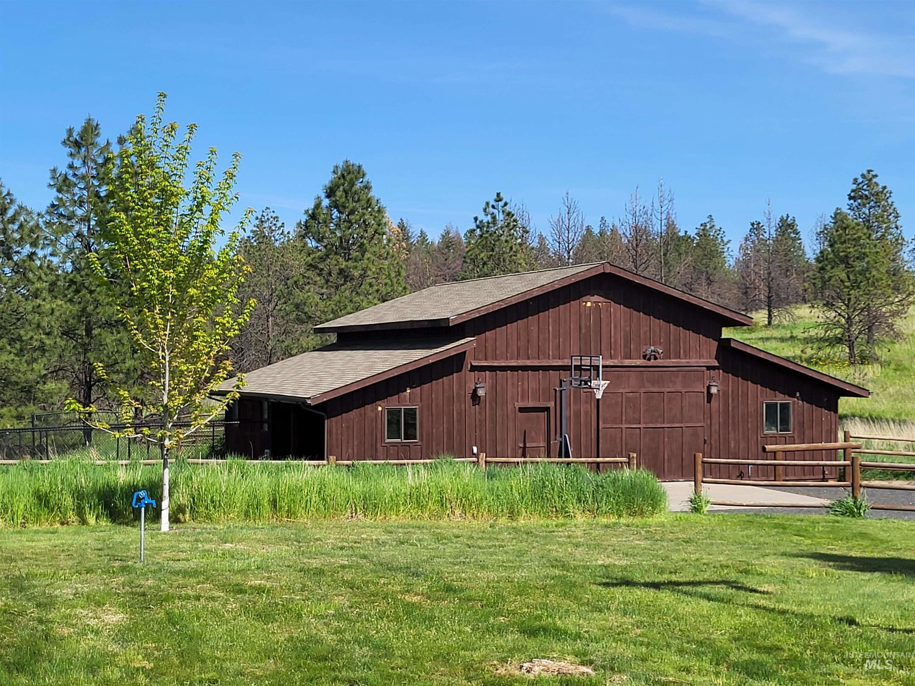 1085 Wallen Road Moscow, ID 83843 - Photo 37 of 50 Large brown barn-style structure featuring vertical wood siding, a multi-pitch roof, and multiple exterior lighting fixtures