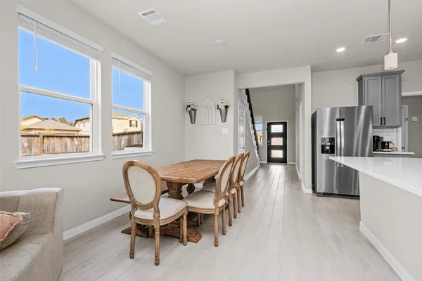 a dining room with stainless steel appliances furniture a window and kitchen view