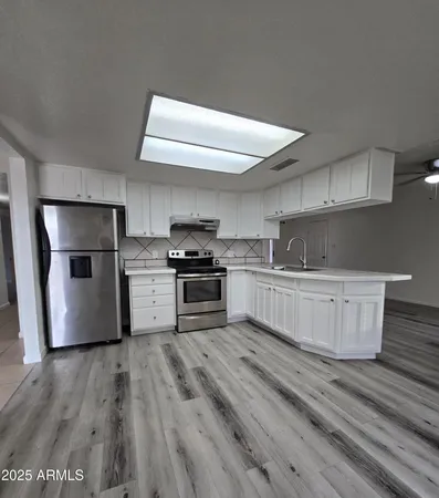 a kitchen with stainless steel appliances wooden floor and a sink