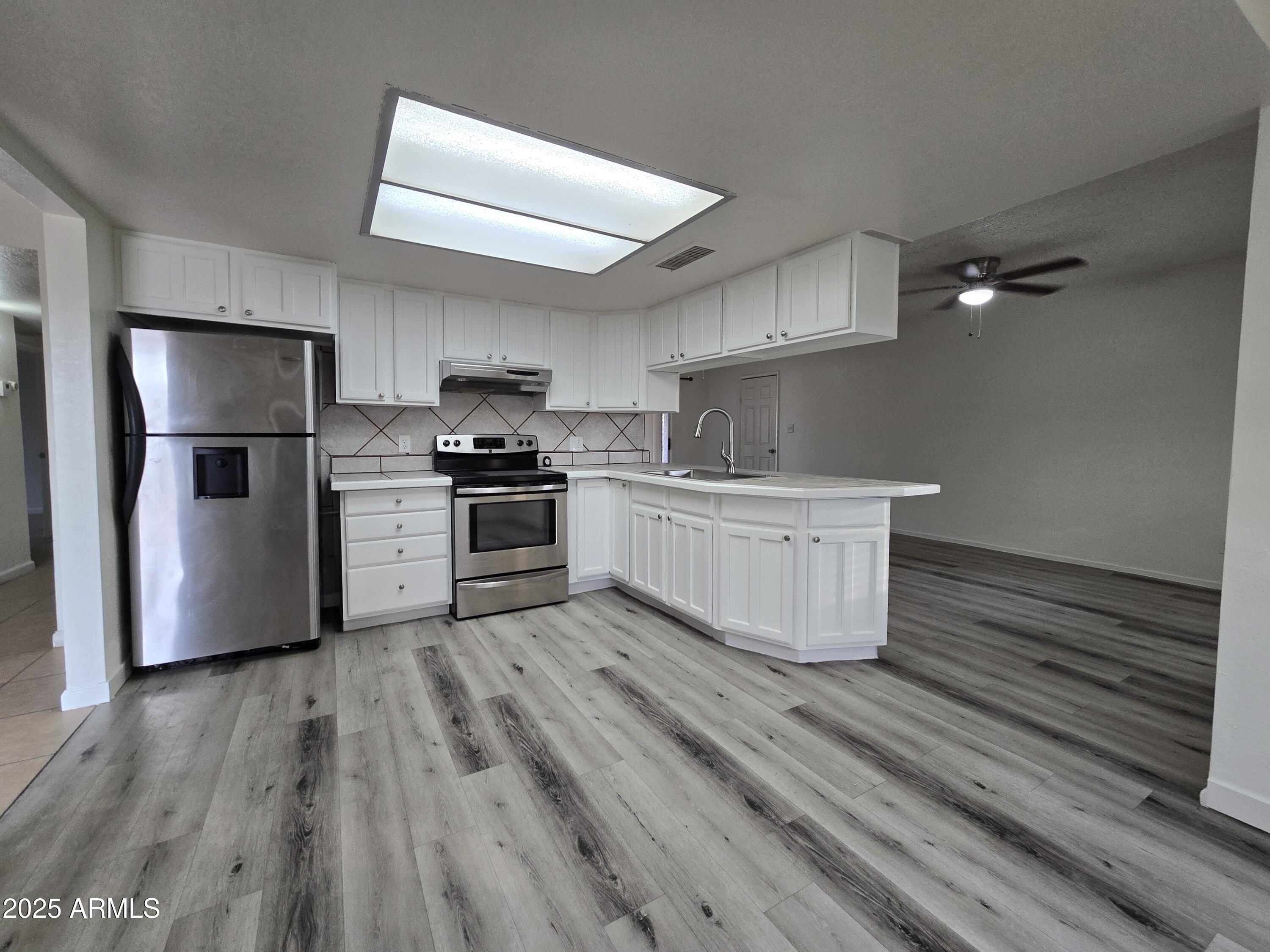 7752 West Flower Street Phoenix, AZ 85033 - Photo 9 of 30 a kitchen with a sink a refrigerator and cabinets