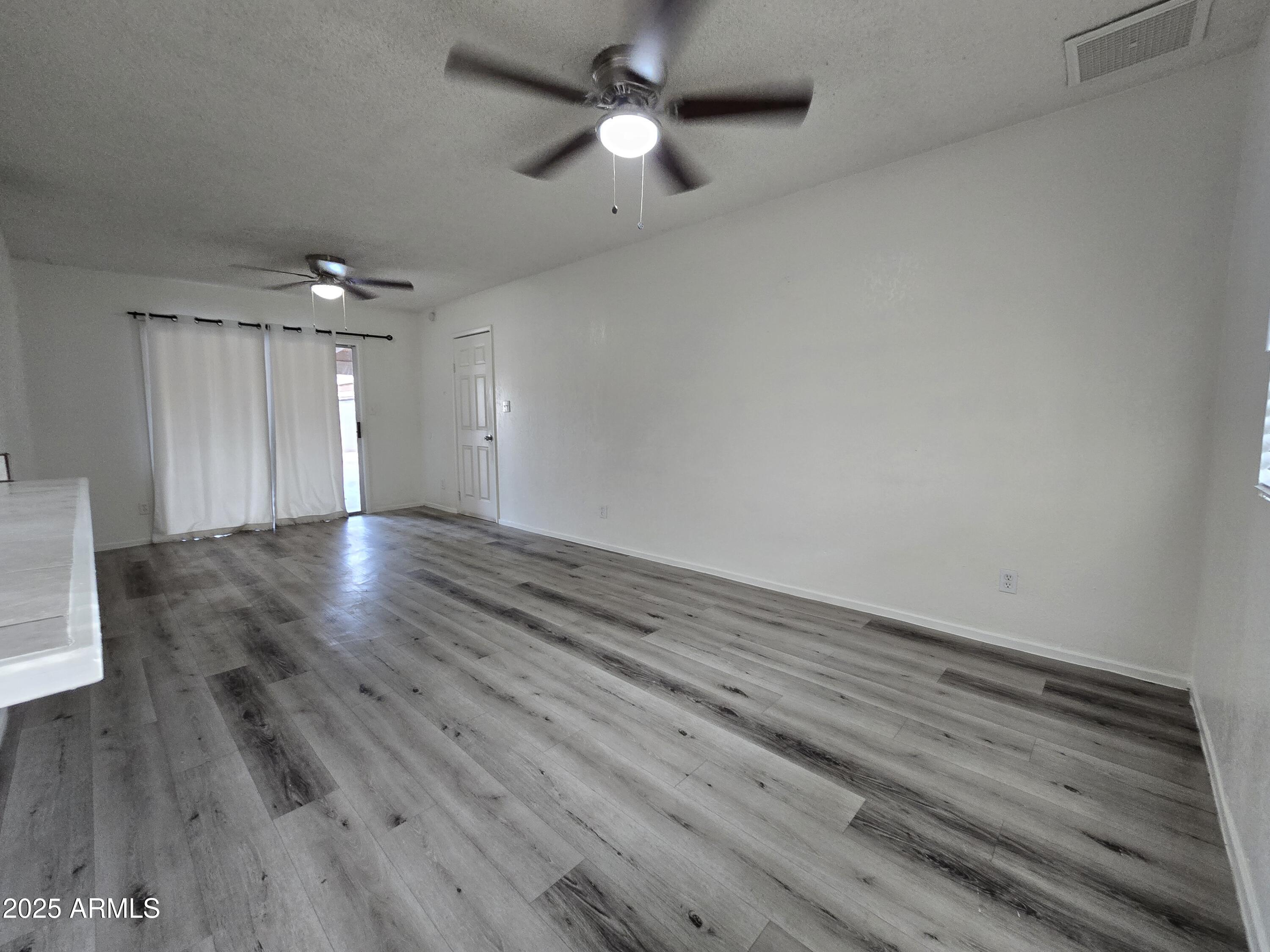 7752 West Flower Street Phoenix, AZ 85033 - Photo 10 of 30 an empty room with wooden floor ceiling fan and window