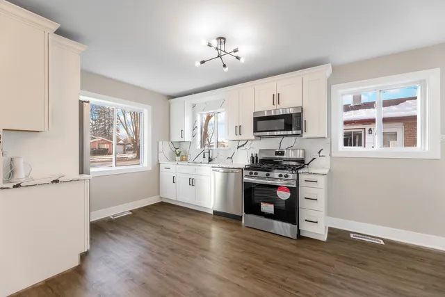 a kitchen with stainless steel appliances granite countertop a stove and a wooden floors