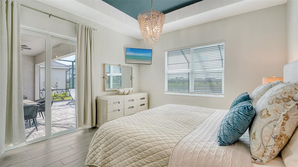12716 Tulum Loop Venice, FL 34293 - Photo 18 of 97 a bedroom with a large bed and a chandelier
