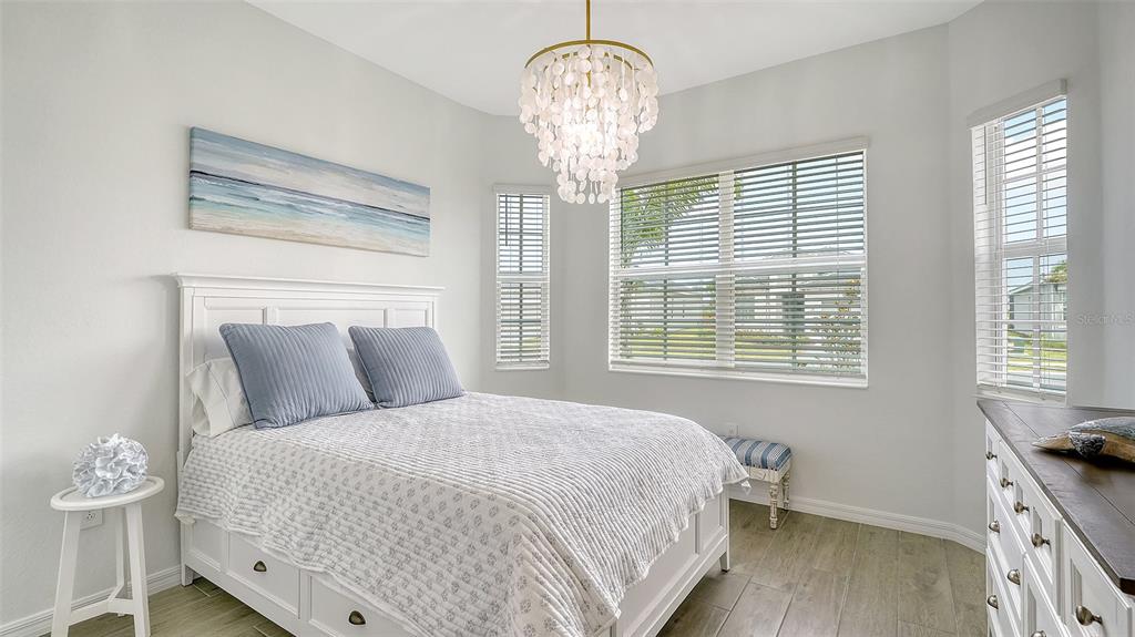 12716 Tulum Loop Venice, FL 34293 - Photo 28 of 97 a bedroom with a bed and a chandelier