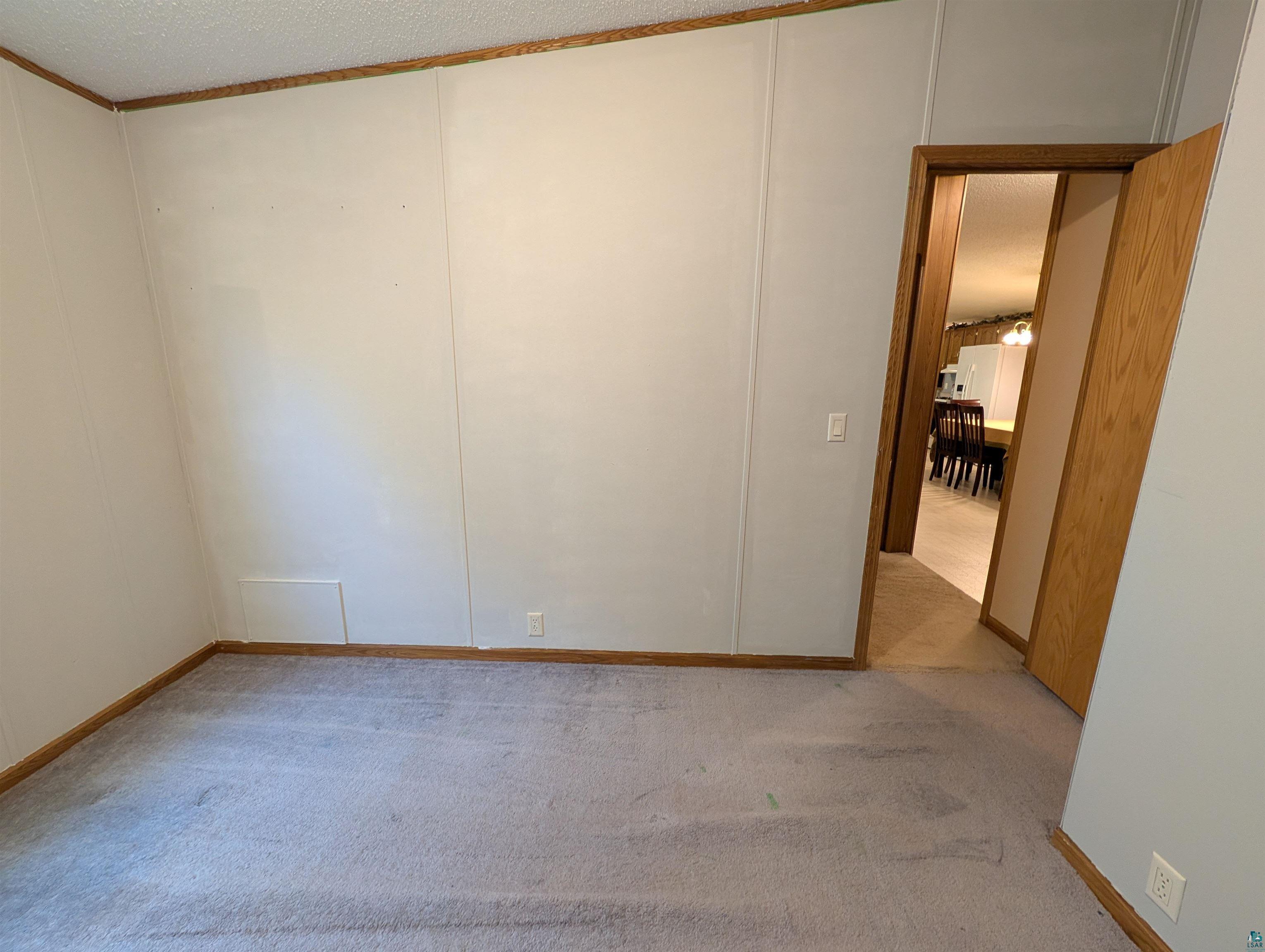 3945 Maple Street Kettle River, MN 55757 - Photo 23 of 41 Interior room featuring light gray paneled walls with wood trim, gray carpet flooring, and a wood-framed doorway