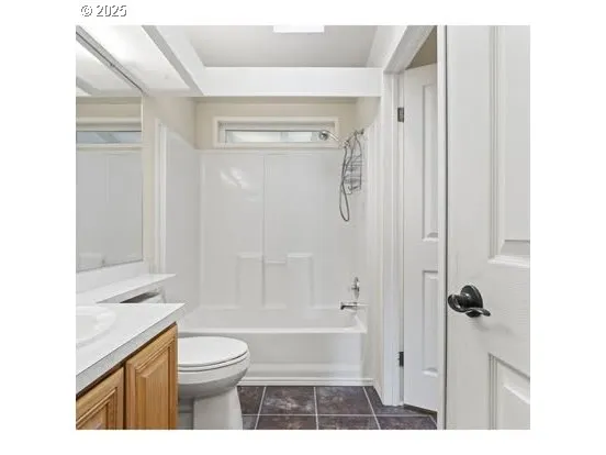 a bathroom with a granite countertop bathtub shower sink vanity and a toilet