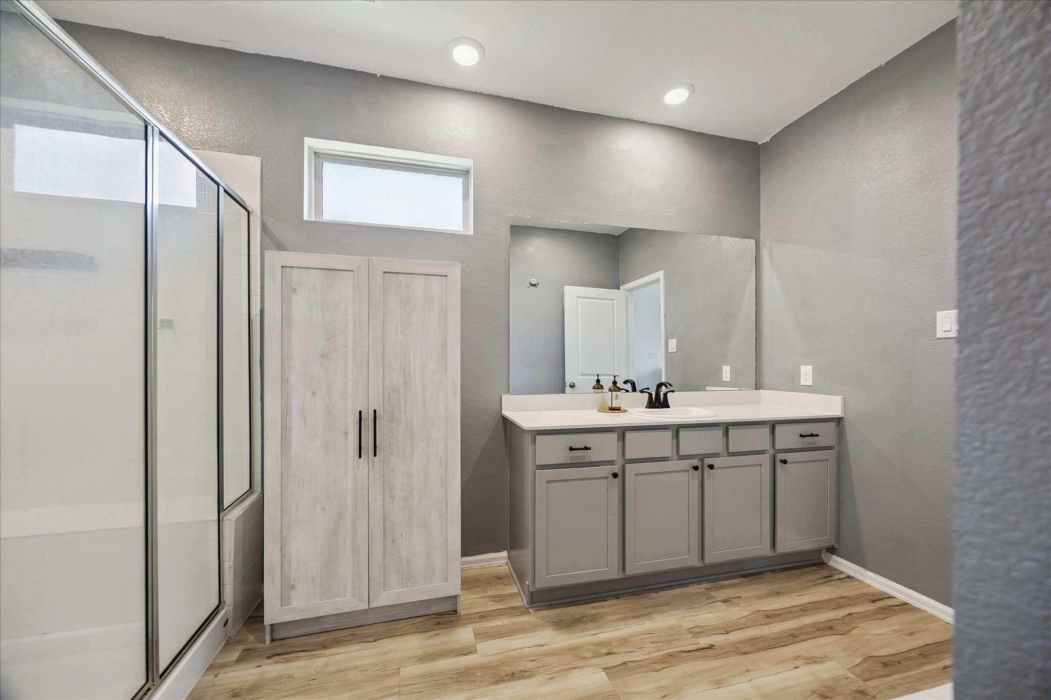 3812 Moss Hl Road Rosenberg, TX 77469 - Photo 14 of 20 This bathroom features a modern design with gray walls, a sleek vanity with ample storage, a large mirror, and a glass-enclosed shower.